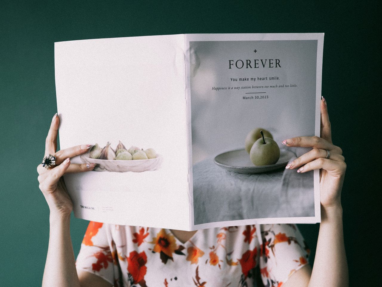 services-01 Woman in floral dress holding a magazine with a 'FOREVER' cover under a green background.