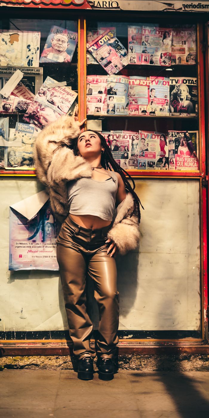 Fashionable woman in fur coat posed confidently against a vibrant magazine stand. Urban street style at its best.