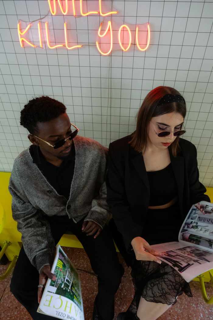 services-03 Stylish couple reading in a modern interior with neon sign reading 'Will Kill You'.